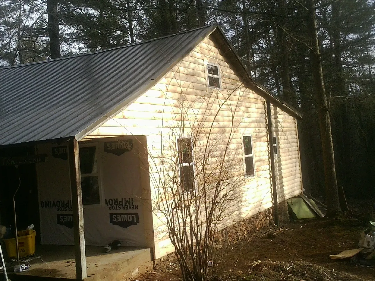 Log siding gable end under a dark metal roof edge in Sharps Chapel