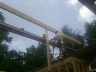 Carpenter setting a ridge beam over a new addition frame — Ice Dam Removal by Roofing Brothers in Sharps Chapel