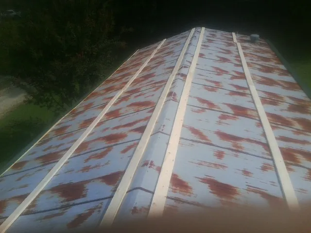 Rusted metal roof panels with new wood purlins before replacement — Storm Damage Roof Repair in Sharps Chapel by Roofing Brothers