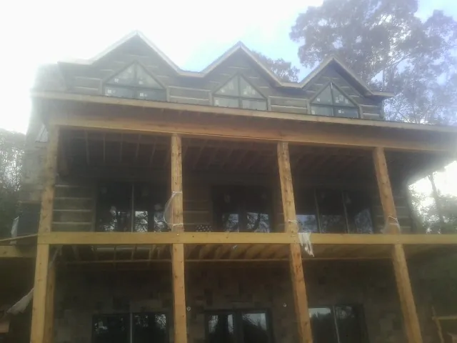 Dormers and porch framing on a large log home under construction — Roof Coating work by our crew in Sharps Chapel