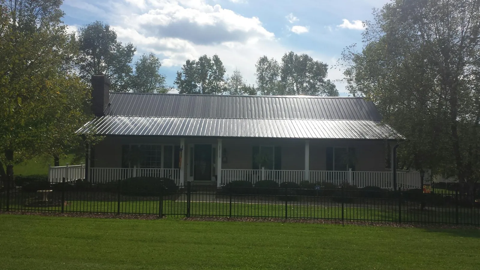 Gray metal roof on a brick ranch with a full width front porch — Gutter Guard Installation work by our crew in Sharps Chapel